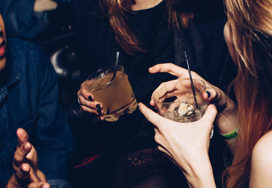 two women talking while holding drinking glasses