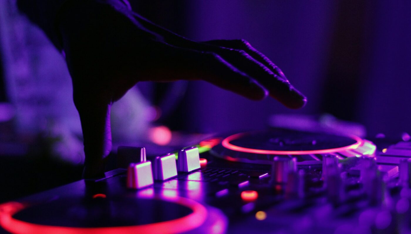 selective focus silhouette photography of man playing red-lighted DJ terminal