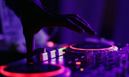 selective focus silhouette photography of man playing red-lighted DJ terminal